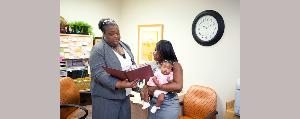Photograph of a mother holding her child and talking with the health navigator in the Educare Atlanta facility.