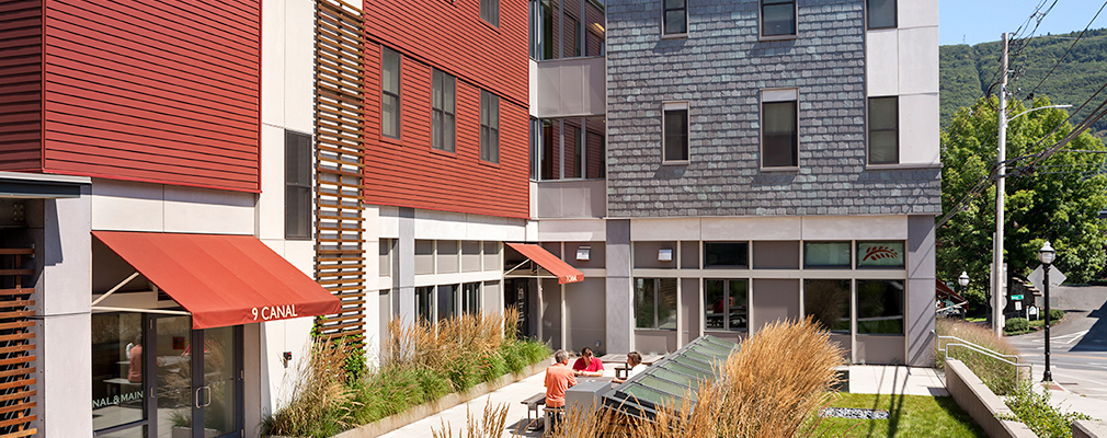 Photograph of a landscaped seating area in front of the three-story section of the building.