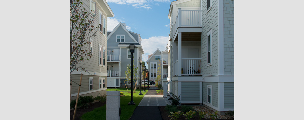 Photograph of several four-story residential buildings adjacent to a walkway.