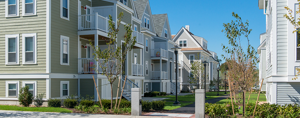 Photograph of several three-story multifamily buildings on either side of a pedestrian walkway.