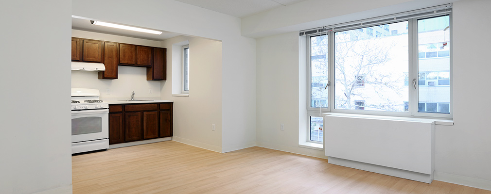 Photograph of the living room/kitchen areas featuring a large window extending to within a few inches of the floor.