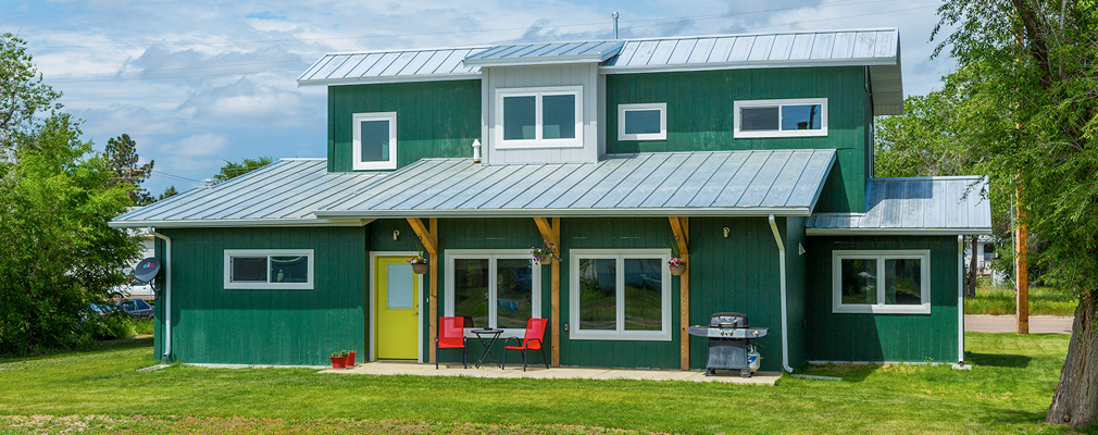 Photograph of the rear of a single-family detached house with several large windows to capture natural light and awnings and with overhangs on each of the two stories for shading in warmer months.