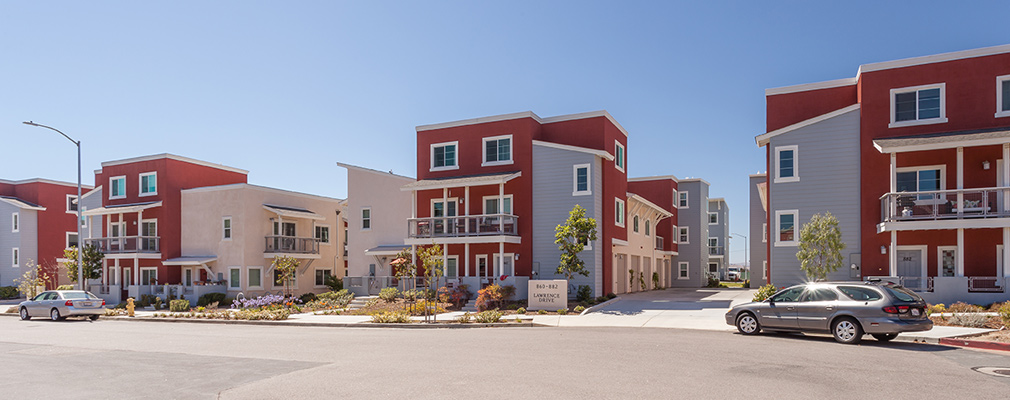 Photograph showing two street faces of a block of two- and three-story townhouses.