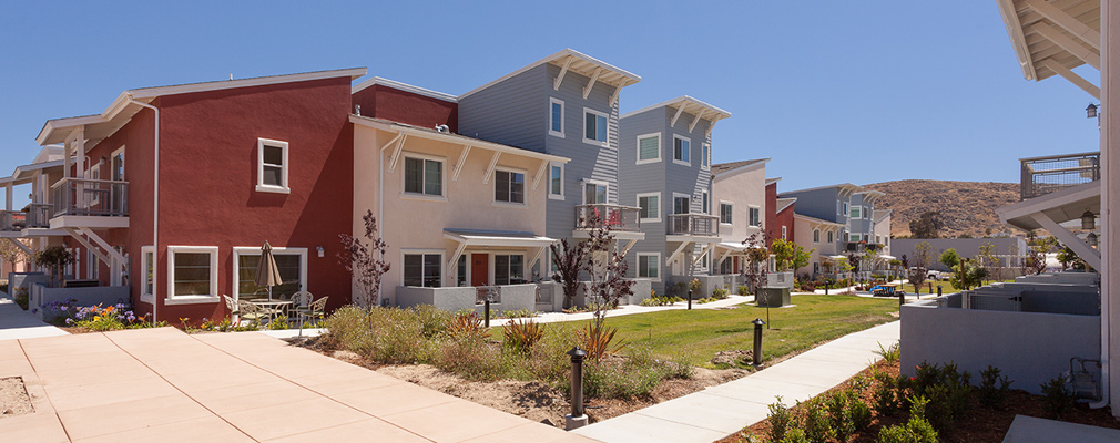 Photograph of the front façades of two- and three-story townhouse buildings facing the common greenspace.