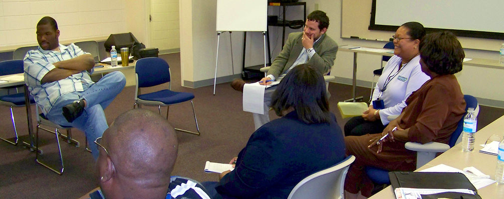 Photograph of six people sitting in a circle in a meeting room.