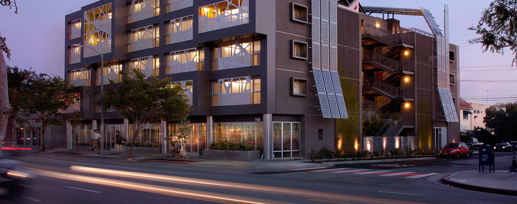 Photograph of the two street façades of the five story building with two sets of solar panels on the roof extending down four stories on the side façade.