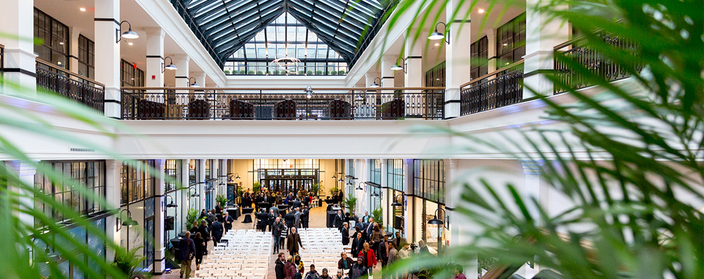 Photograph of a two-story atrium and a group of people milling about temporary seating on the first floor.