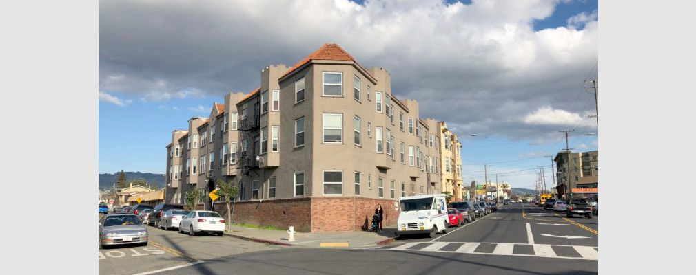 Photograph of two façades of a three-story multifamily residential building.