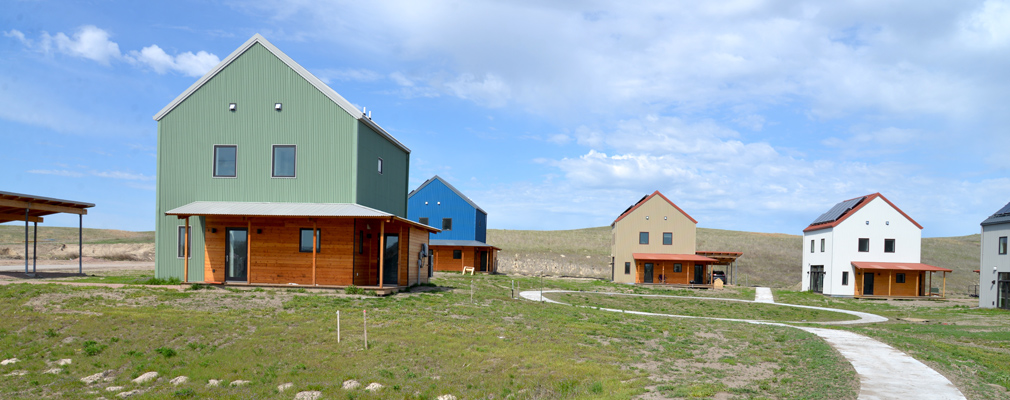 Photograph of five 2-story houses, each with a with covered corner porch, arranged in a circle.