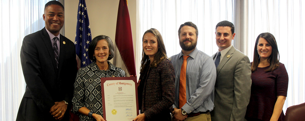 Photograph of six men and women holding a county commission proclamation recognizing Your Way Home’s achievements.