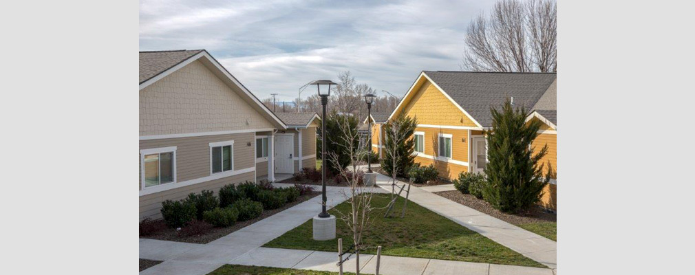 Photograph of two single-story duplexes enclosing a small open area with landscaping and walking paths.