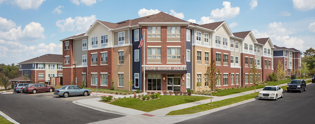 Photograph of the front and side façades of an L-shaped, three-story building, with two additional buildings at either end.