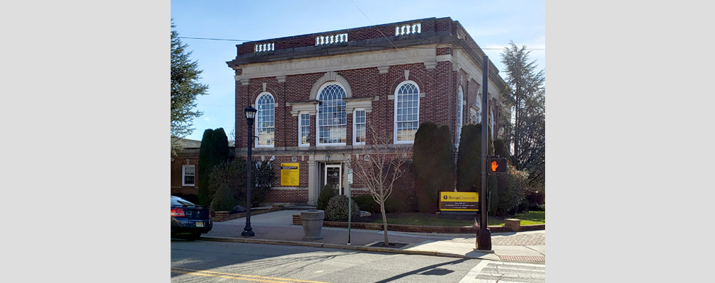 Photograph of the front façade of a two-story, brick commercial building with a neoclassical design.