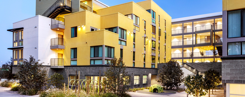 Photograph of a children’s play area framed on three sides by a multistory residential building.