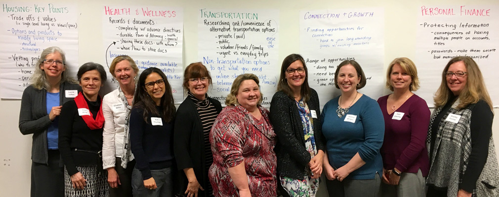 Photograph of ten women standing in front of flipboard sheets with meeting notes.