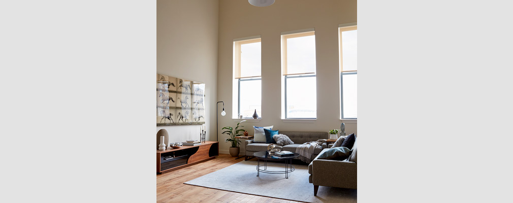 Photograph of a living room with two sofas and other furniture and large windows along one of the walls.