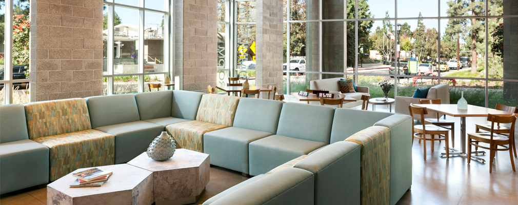 Photograph of a community room with a couch in the foreground and tables in the middleground. 