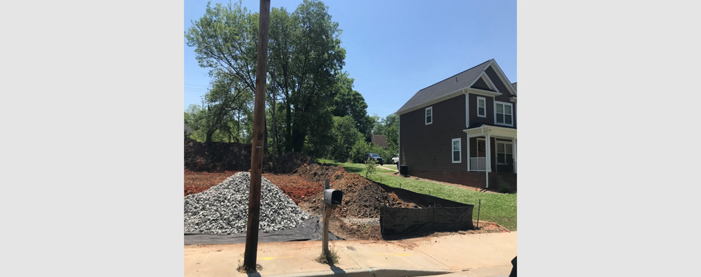 Photograph of a graded lot next to a newly built house.