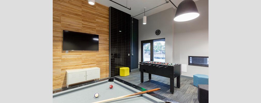 Photograph of a large room with a foosball table, pool table, and television set. 