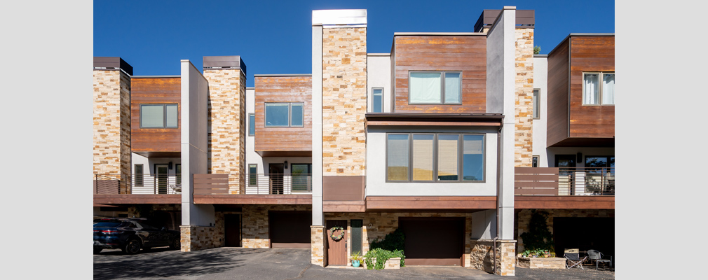 Photograph of the front façades of four 3-story townhouses.