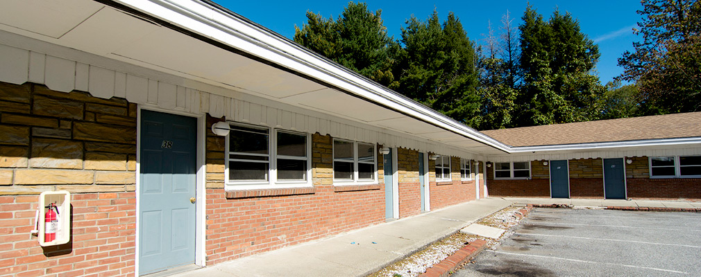 Photograph of the front façade of an L-shaped, one story, multiunit residential building.