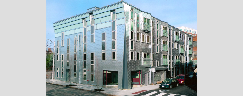 Photograph of two façades of a four-story multifamily building.