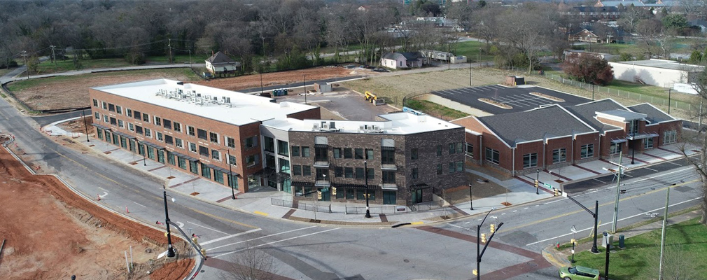 Low-angle aerial photograph of a three-story mixed-use building next to a one-story building.