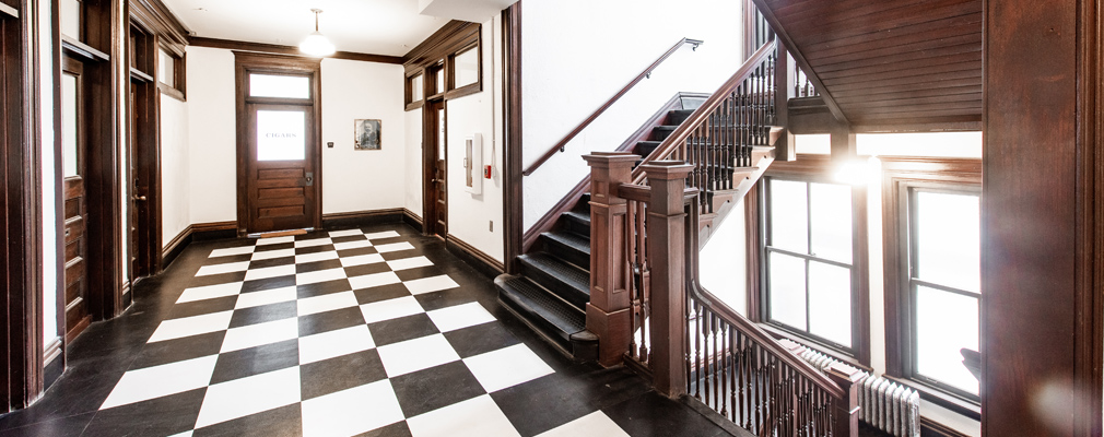 Photograph of a hall featuring historic wooden doors and stairway.