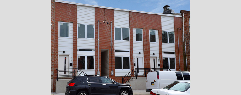 Photograph of the front façades of three 2-story row houses.