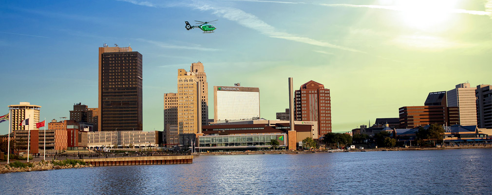Photograph from across the Maumee River of the skyline of the downtown of Toledo, with the renovated steam plant and other ProMedica buildings in the center of the photograph.