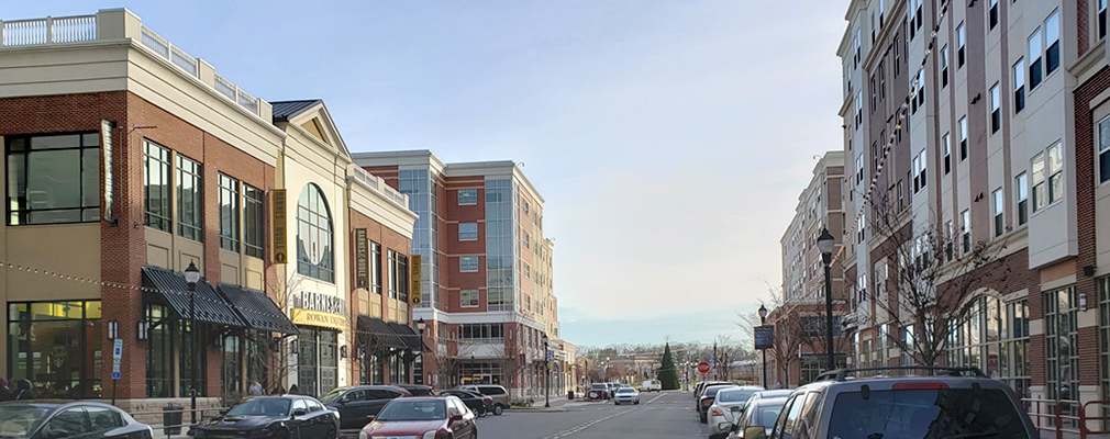 Photograph of multistory mixed-use buildings on both sides of Rowan Boulevard, with the Town Square in the background.