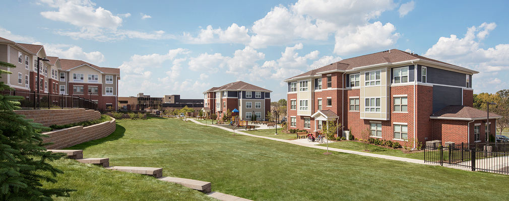 Photograph of a large, sloping greenspace between three residential buildings.