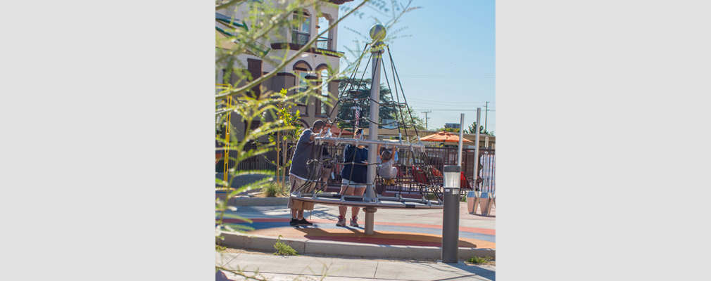 Photograph of a rotating net climber with a three-story multifamily building in the background.