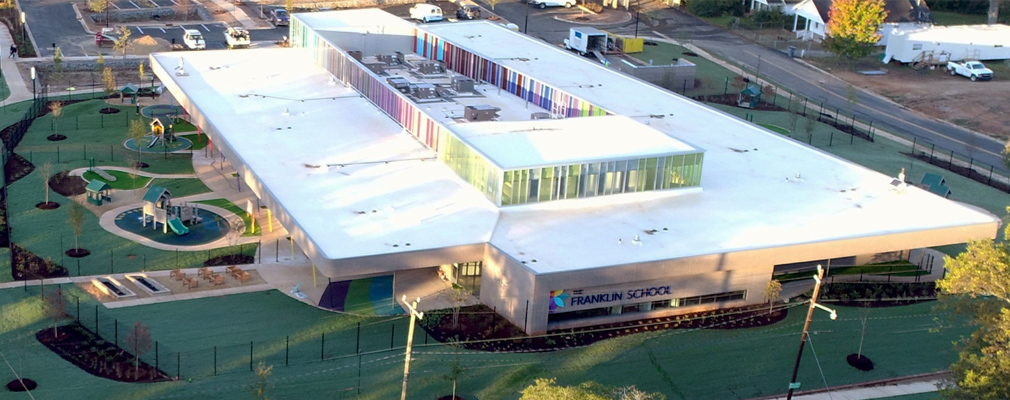 Low-angle aerial photograph of a one-story school building, with play equipment next to the building.