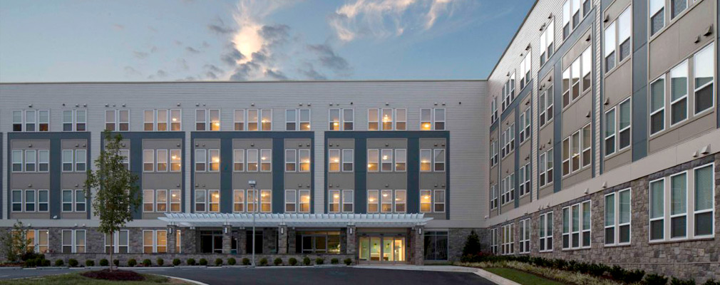 Photograph of two façades of a four-story multifamily building.