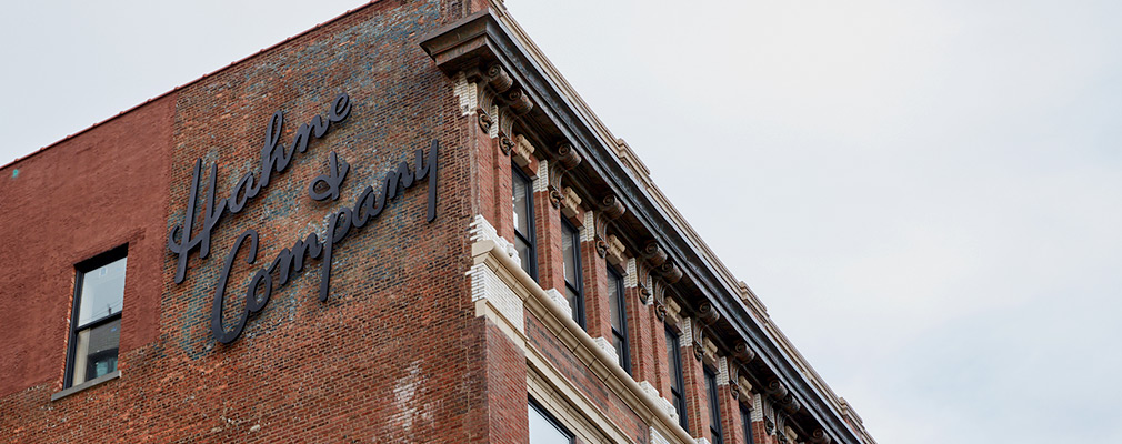 Photograph of the exterior of the Hahne & Co. building, showing the upper two stories of two façades at a corner of the building where a wall sign reading “Hahne & Company” is placed.