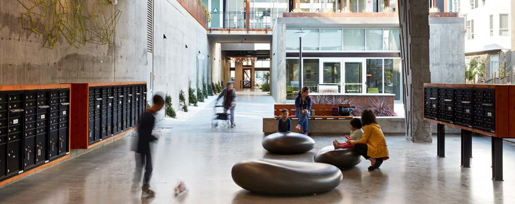 Photograph of several people in Five88’s open-air lobby, with the courtyard in the middle-ground and wings of the apartment building in the background.