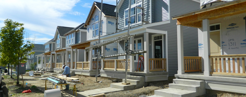 Photograph of the front façades of five 2-story single-family houses under construction.
