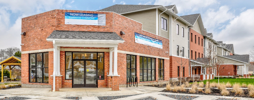 Photograph of a brick storefront attached to a residential building.