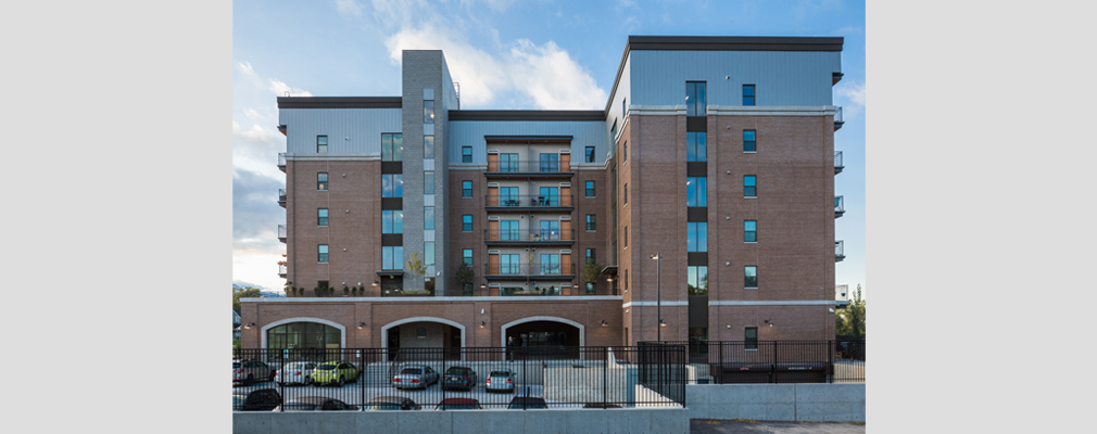 Photograph of a side façade of a six-story building, with a surface parking lot in the foreground.