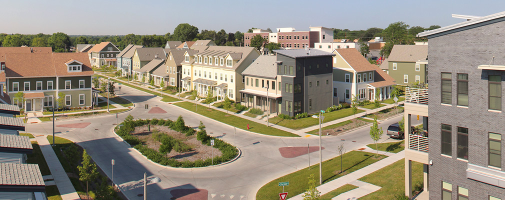 Photograph of a landscaped island in an intersection of four streets lined with two- and three-story residences.