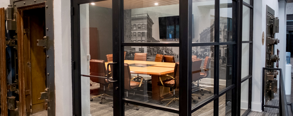 Photograph of a conference table set in a historic bank vault, with an old photograph of the Block22 buildings on a wall in the background.