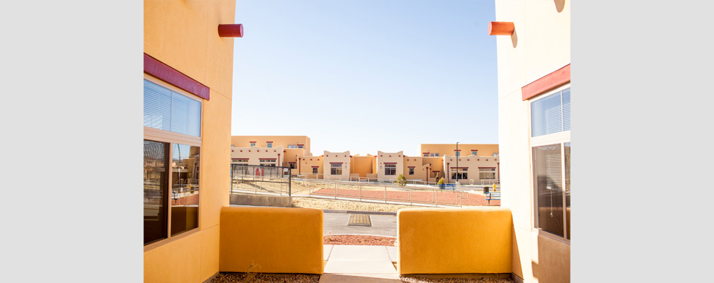 Photograph taken from within a courtyard across the central common space to one- and two-story attached residences in the background.