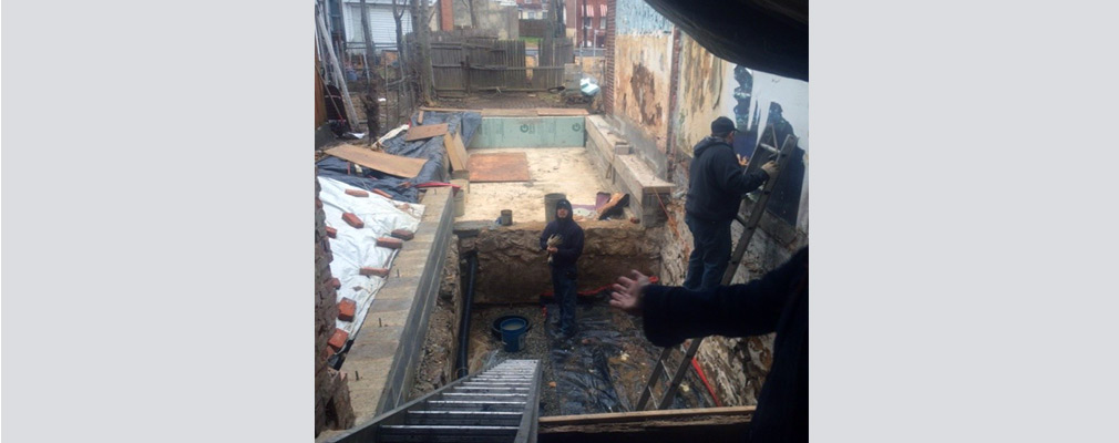 Photograph of three men working at a construction site of a house. 