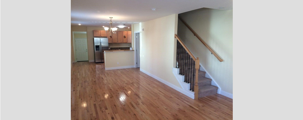 Photograph across a living area to a kitchen showing the open floor plan of a renovated house. 