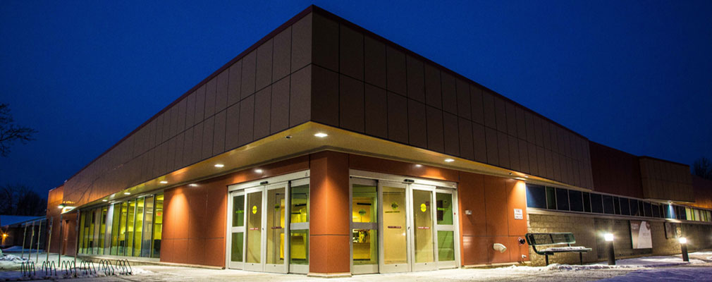 Photograph of the front and side façades of a one-story medical building at night.