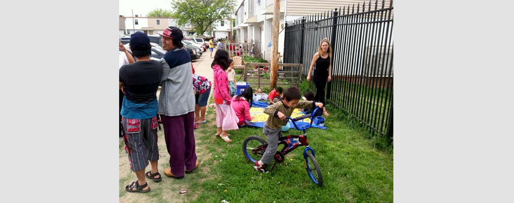 Photograph of children and adults enjoying an outdoor gathering in a housing development. 