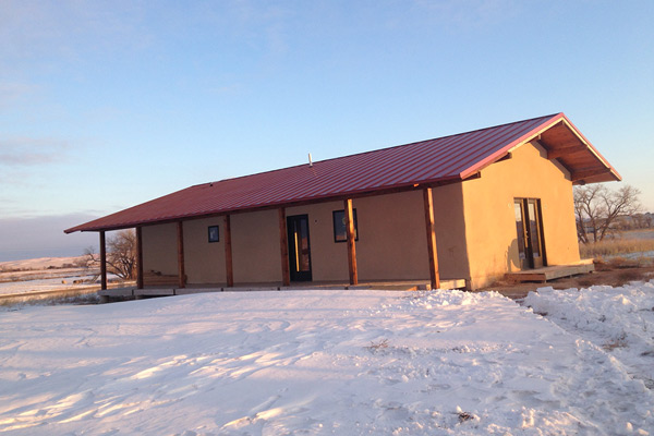Photo showing the front façade and side of a ranch-style house in a snowy field.