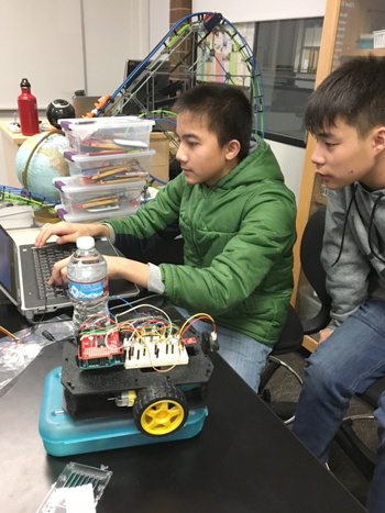 Photograph of two students working on a laptop in class.