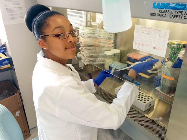 Photograph of a medical student using a pipette under a fume hood.